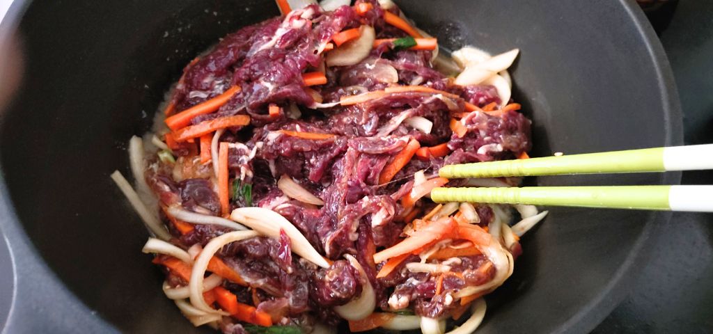 下味をつけた牛肉と野菜を炒めています