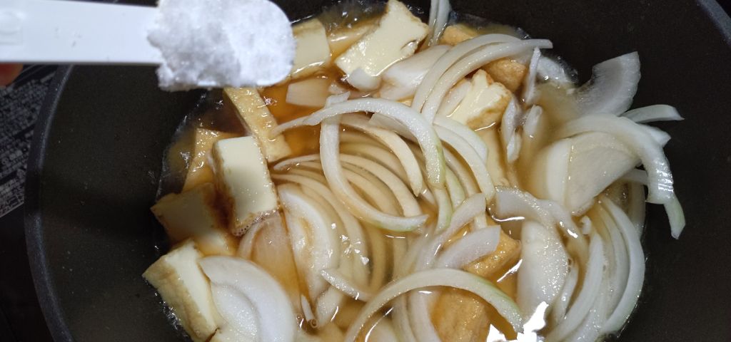 厚揚げと玉ねぎに調味料を加えています